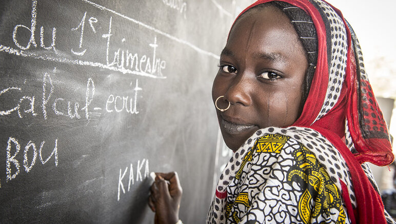 Kaka Marabou écrit son nom sur le tableau de l'école de Yakoua, au lac Tchad. Les réfugiés, les personnes déplacées et les autres communautés vulnerables du bassin du lac Tchad dépendent de l'aide humanitaire pour survivre et l'accès à l'éducation de base est également limité. PAM/Giulio d'Adamo